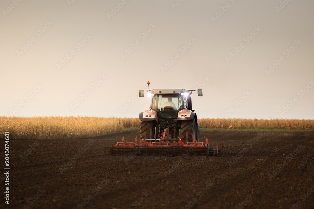 Fototapeta premium Modern tractor working cultivated soil in rural farmland