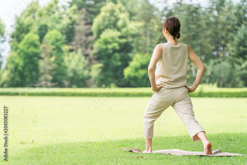 Bild auf Leinwand A woman's back as she does yoga, stretching, and flexibility exercises in a park