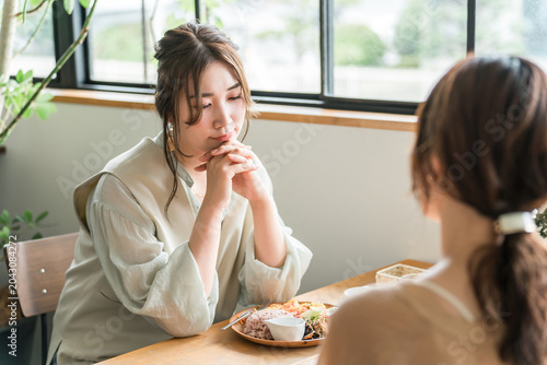 Foto A young Asian woman confides her troubles to a friend at a cafe.