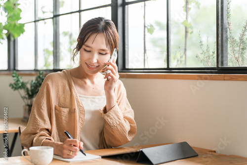 Obraz na płótnie A young Asian woman working remotely/as a digital nomad at a cafe