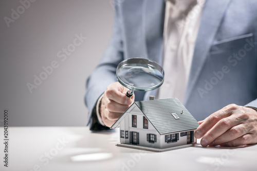 House model with man holding magnifying glass home inspection or searching for a house