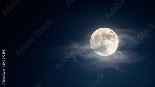 A bright full moon shines through wispy clouds against a dark night sky.