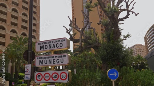 Road signs indicating Monaco and Moneghetti districts surrounded by urban greenery and residential architecture in the heart of the principality 4K. Monaco 7 May 2019

