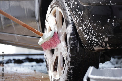 Cuadro en lienzo Cleaning car wheel with soapy brush and bubbles