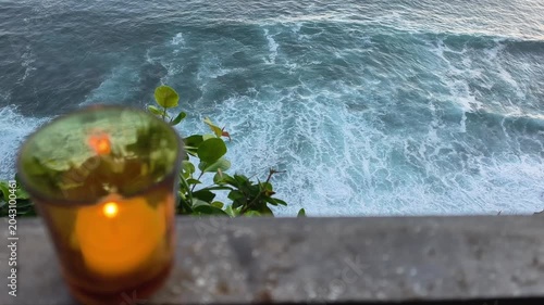 Warm candlelight flame set against a dramatic top view of powerful sea waves breaking on the tropical coast in the morning. Uluwatu Beach, Bali
