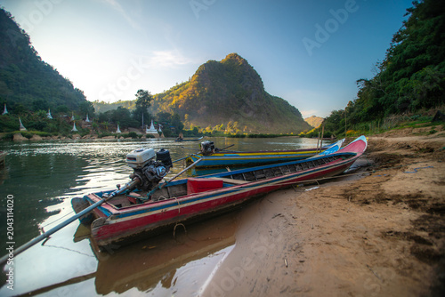 Foto A pier with fishing boats along the river, situated in a natural setting with a pagoda and mountains