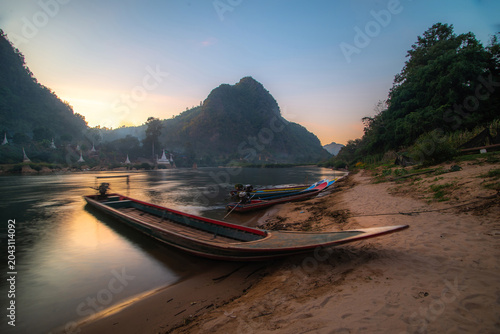 Foto A pier with fishing boats along the river, situated in a natural setting with a pagoda and mountains