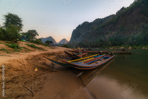 Foto A pier with fishing boats along the river, situated in a natural setting with a pagoda and mountains
