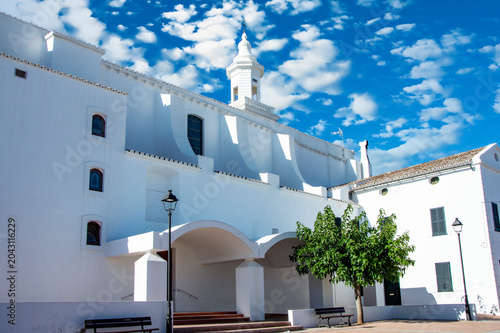 Tableau sur toile Iglesia Parroquial de San Luis Menorca, un día soleado con cielo azul y nubes blancas
