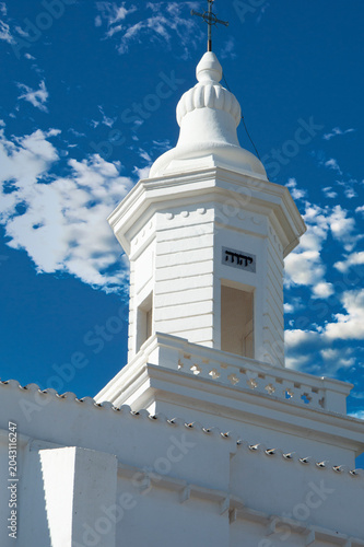 Foto Iglesia Parroquial de San Luis Menorca, un día soleado con cielo azul y nubes blancas