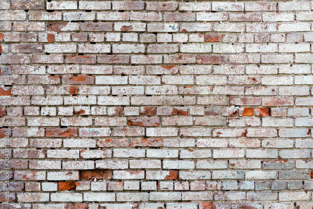 Naklejka premium Damaged brick wall background with faded white paint