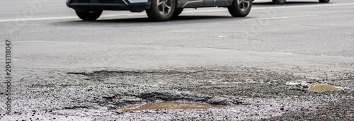 Canvas-taulu Urban street with large puddles formed after rainfall, causing difficulties for vehicles and highlighting poor drainage, road damage, and challenging driving conditions in city traffic