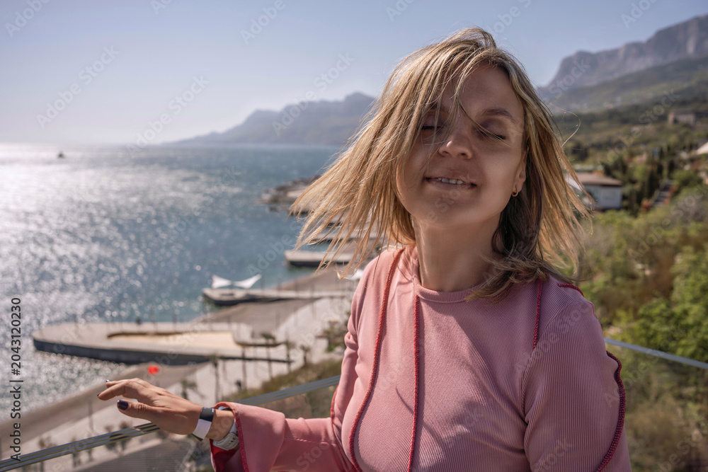 Fototapeta premium Woman sea balcony enjoying the ocean breeze on a sunny hotel terrace