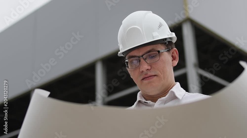 Engineer at a construction site.White hard hat. Man wearing glasses. Slow motion video.. High quality 4k footage