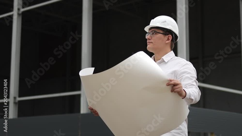 Engineer at a construction site.White hard hat. White shirt. Metal structures. Slow motion video. High quality 4k footage