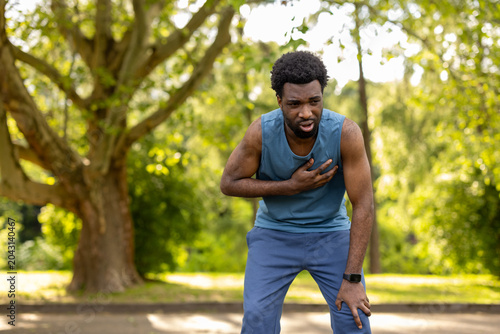 Foto Young adult man stopping his outdoor run due to sudden chest discomfort, indicat