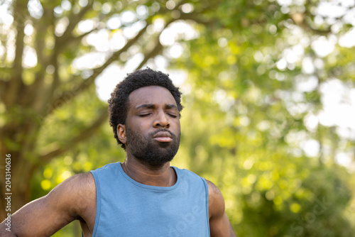 Young handsome man with closed eyes finding inner peace and mindful focus through outdoor meditation, connecting with nature for mental and physical wellness