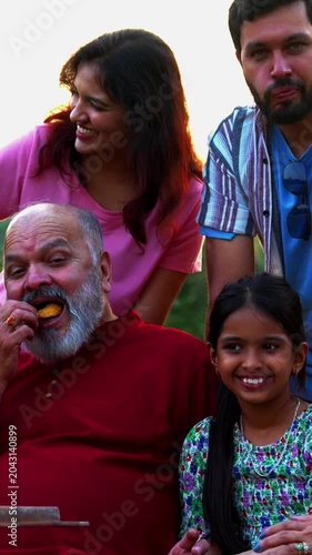 Indian family sitting on bench together outdoors smiling at camera, enjoying warm bonding moments, sharing fun conversations, cheerful laughter, and relaxed quality time outdoors