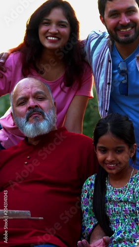 Indian family sitting on bench together outdoors smiling at camera, enjoying warm bonding moments, sharing fun conversations, cheerful laughter, and relaxed quality time outdoors