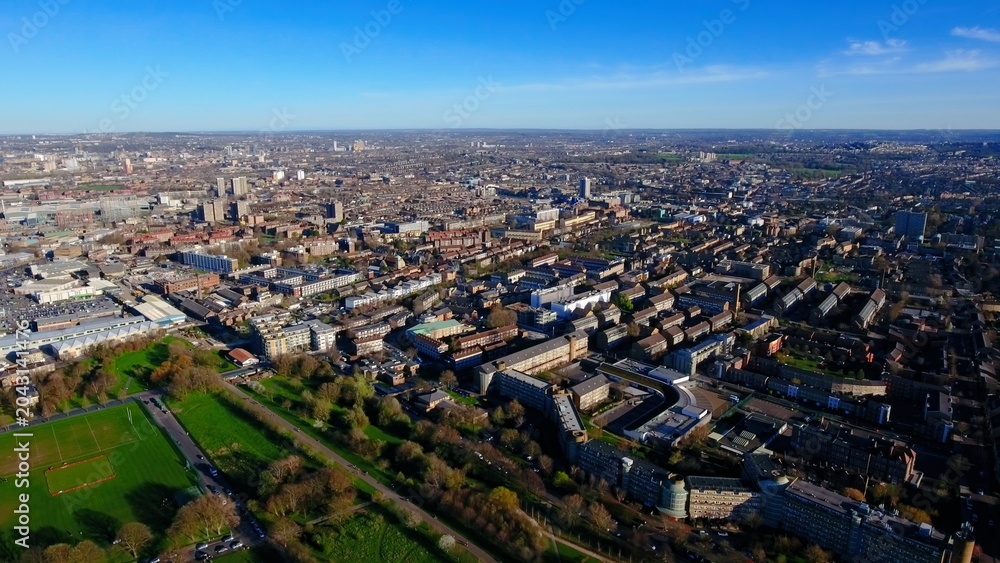 Fototapeta premium 4K aerial drone view of a South London residential neighborhood. Wide cityscape featuring urban housing estates, Burgess Park, and sports pitches.