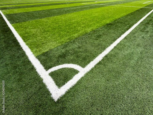 Corner of a soccer field with white boundary lines on green grass turf in an empty outdoor stadium