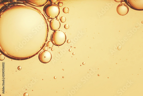 Luxury cosmetic gold serum macro droplets with clear copyspace backdrop