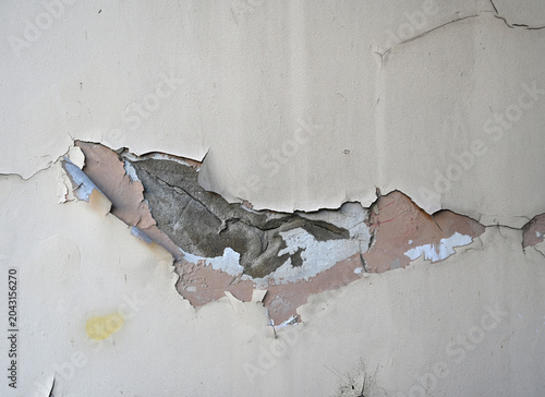 Wall with peeling paint shows layers of damage in a worn building in a city during daylight hours