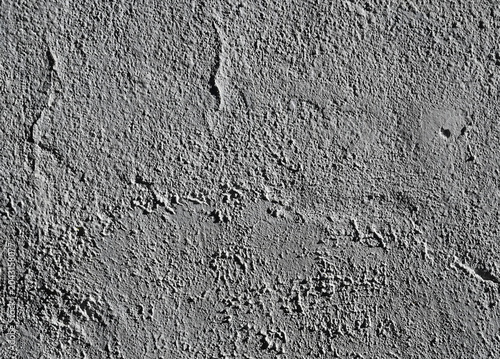 Gray textured wall showing rough surface and patterns during daylight hours in an outdoor setting