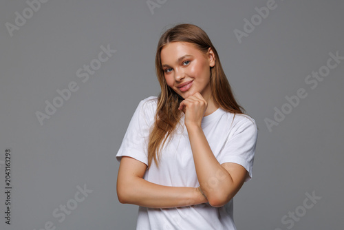 Young woman is thinking with her hand on chin isolated on gray background