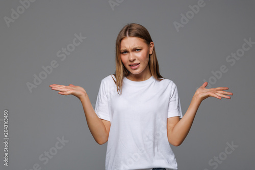 Schilderij op canvas Young woman spreads hands sideways, smirks face, feels doubt while makes choice