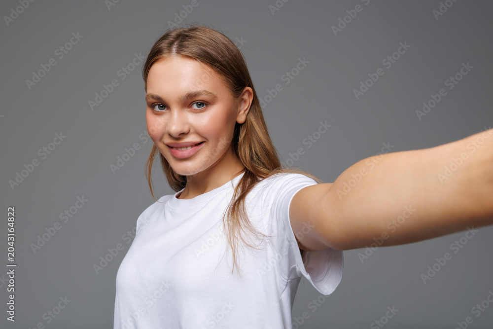 Obraz premium Beautiful woman make selfie by camera over isolated white background