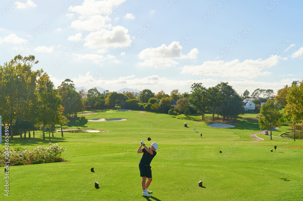 Obraz premium Man swinging golf club on golf course