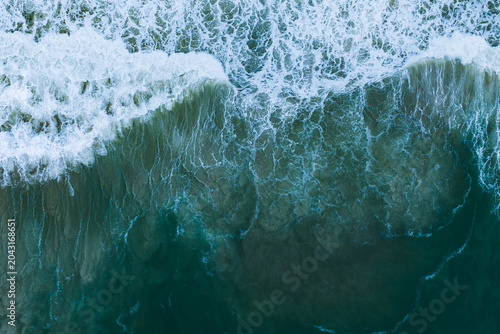 Obraz na plátně Aerial view shows foamy surf feathering over dark teal water along Cape Town sho