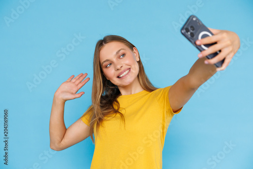 Young woman take selfie on phone isolated on blue background