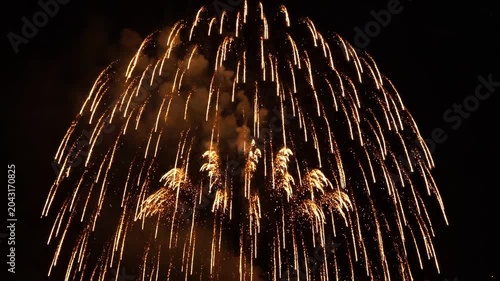 Golden fireworks explode with dazzling light trails and smoke against a dark night sky creating a festive and celebratory atmosphere for holidays and special 4k Video