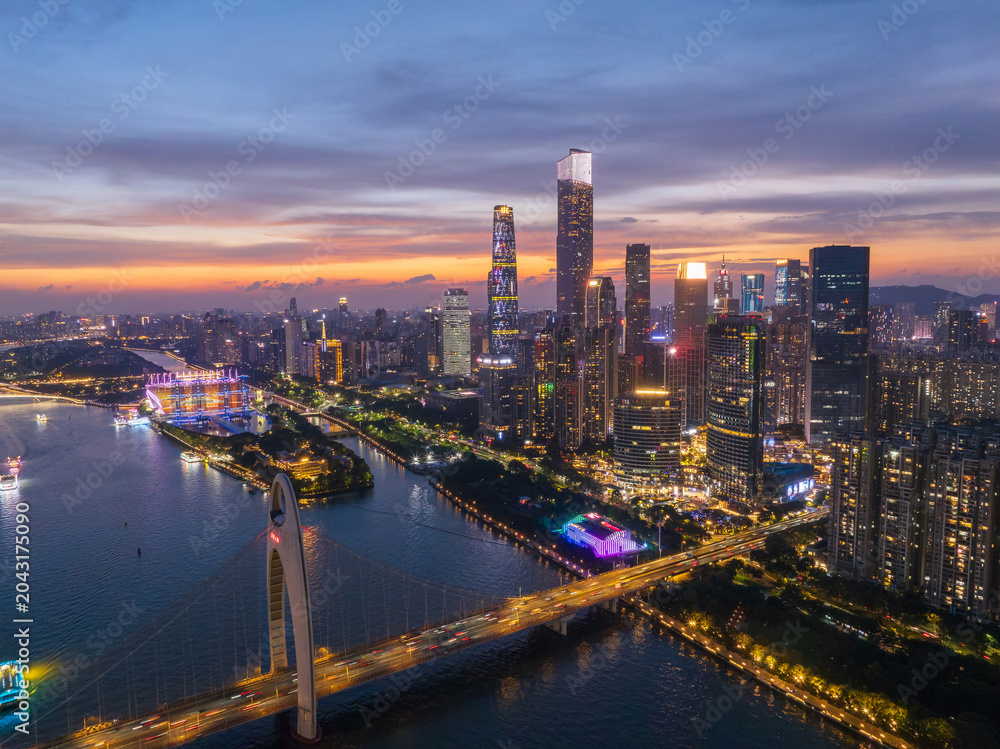 Fototapeta premium Aerial View of Guangzhou Skyline at Dusk with Illuminated Buildings and River