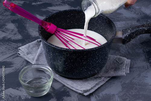 Cuadro en lienzo Milk is poured into a saucepan