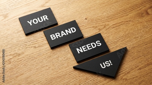 Your Brand Needs Us message on black blocks, marketing agency branding concept, professional business services slogan on wooden background