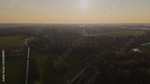 Wide aerial orbit over Vlijmen town and Dutch countryside at Golden Hour
