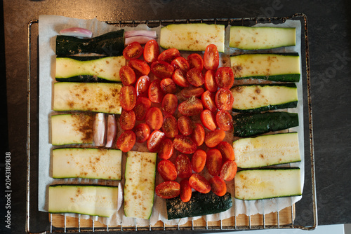 Cut cherry tomatoes Zucchini and onion on a baking rack