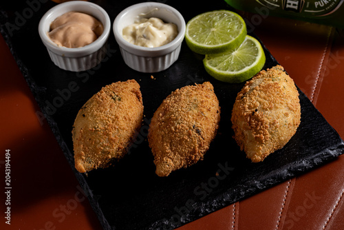 Bild auf Leinwand Fried Brazilian Bolinho Croquettes on Slate Platter with Dipping Sauces and Lime