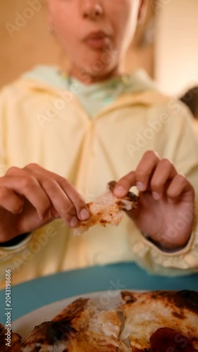 Teenage woman relaxes as she dips crust into flavorful sauce