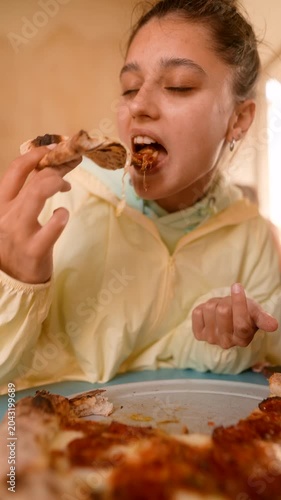 Young girl pulls cheesy strands under warm restaurant lighting