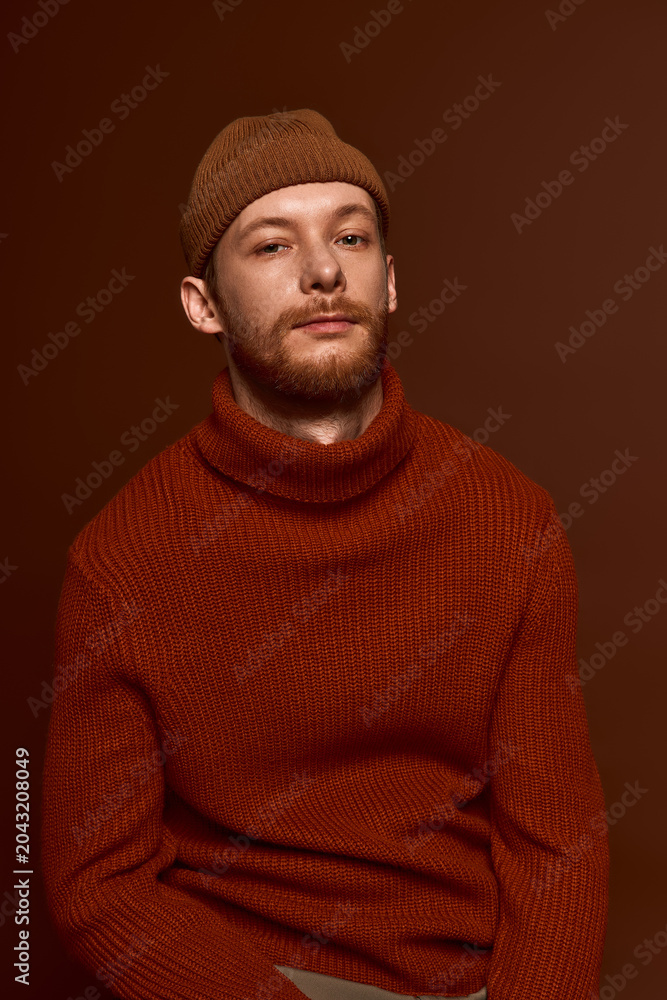 Fototapeta premium Handsome red haired man in stylish attire poses in warm toned setting with captivating charm.