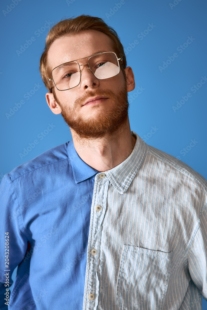 Obraz premium Red haired man showcases modern fashion with unique style against a vibrant blue backdrop.