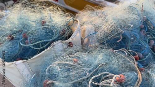 Fishing nets in sunlight showcasing tangles of blue fibers and ropes, providing nautical background