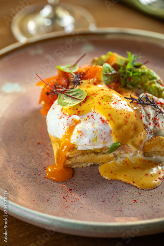 Elegant brunch dish with poached eggs hollandaise sauce and fresh vegetables served on ceramic plate