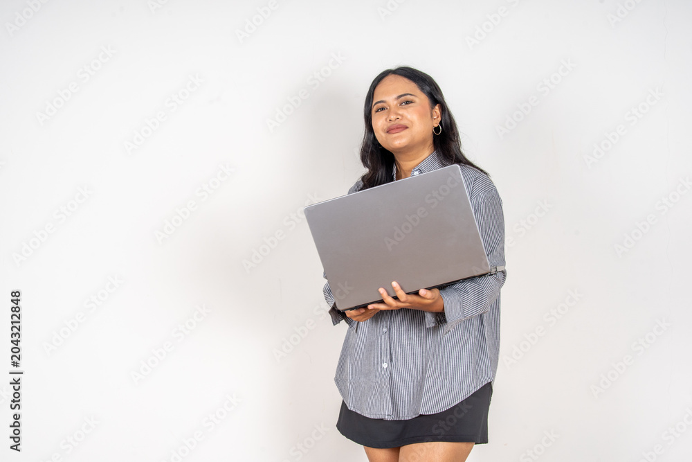 Obraz premium Young woman holds laptop with a joyful expression. She wears a casual striped shirt and dark skirt. Her gaze upward suggests excitement or inspiration. Simple white background highlights her