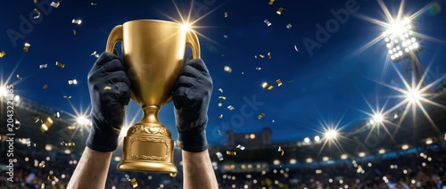 Champion Hands Holding Gold Trophy Cup Under Stadium Lights with Confetti Victory Celebration Sport