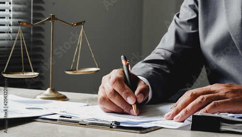 Foto Hand writes legal document near golden scale